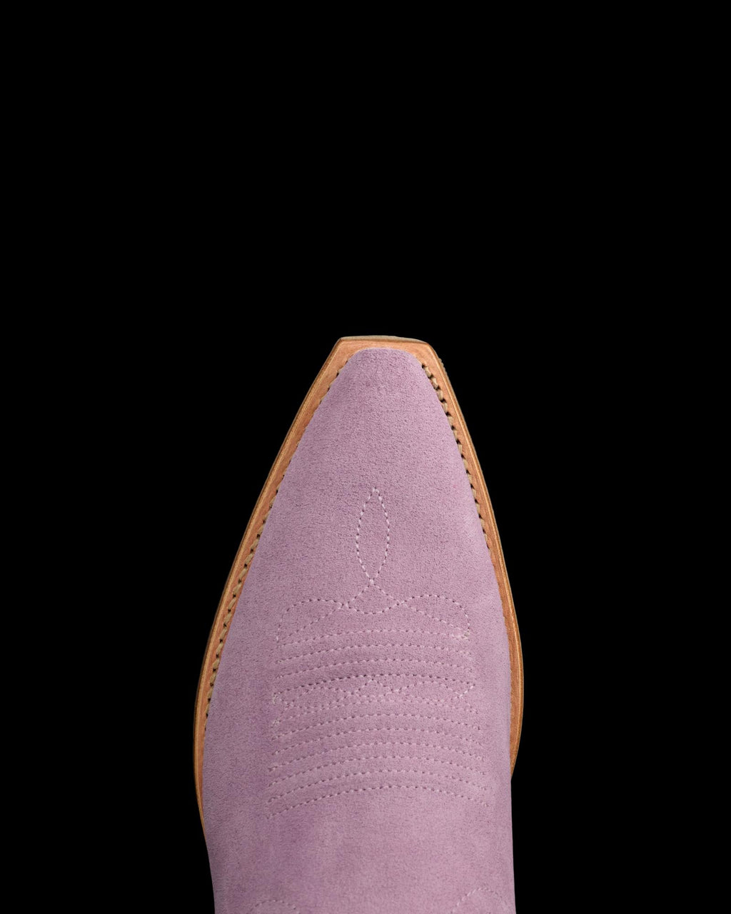 The Annie in Lavender Suede. Close-up of the pointed toe of a Lavender Suede cowboy boot with decorative stitching and a light brown sole, set against a white background.