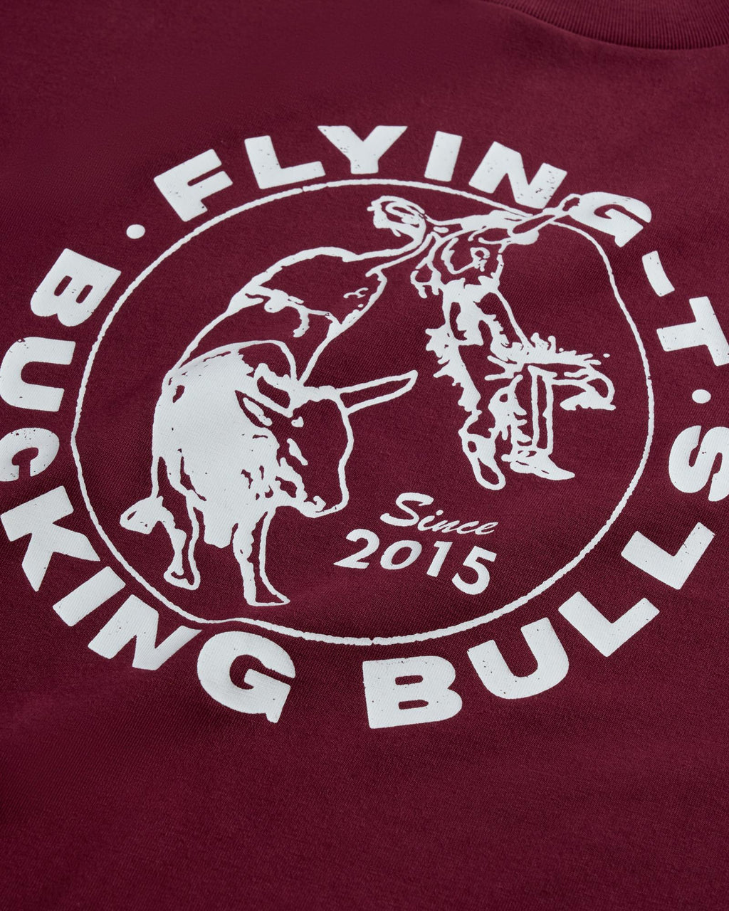 Maroon shirt with a white circular logo reading "Flying T's Bucking Bulls Since 2015," featuring a bull and a rodeo rider graphic.