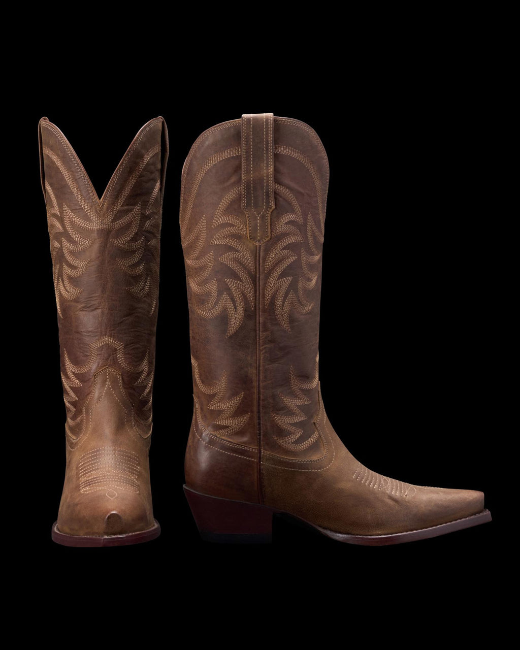 A pair of brown leather cowboy boots with intricate stitching designs, shown in side and back view against a black background.