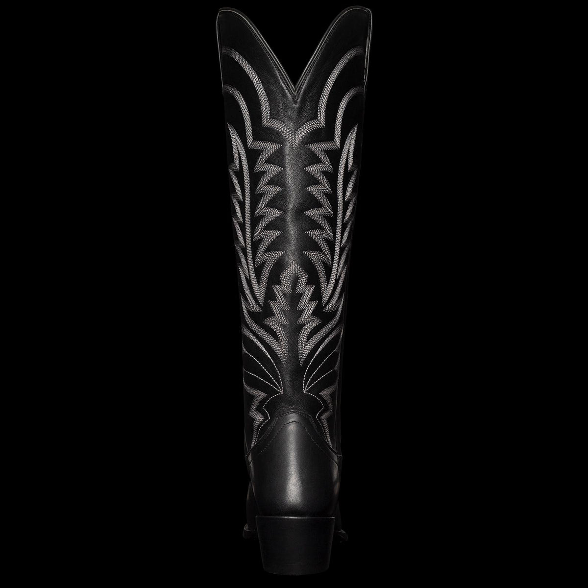 A tall, black cowboy boot with intricate white stitching and a pointed toe, viewed from the front.
