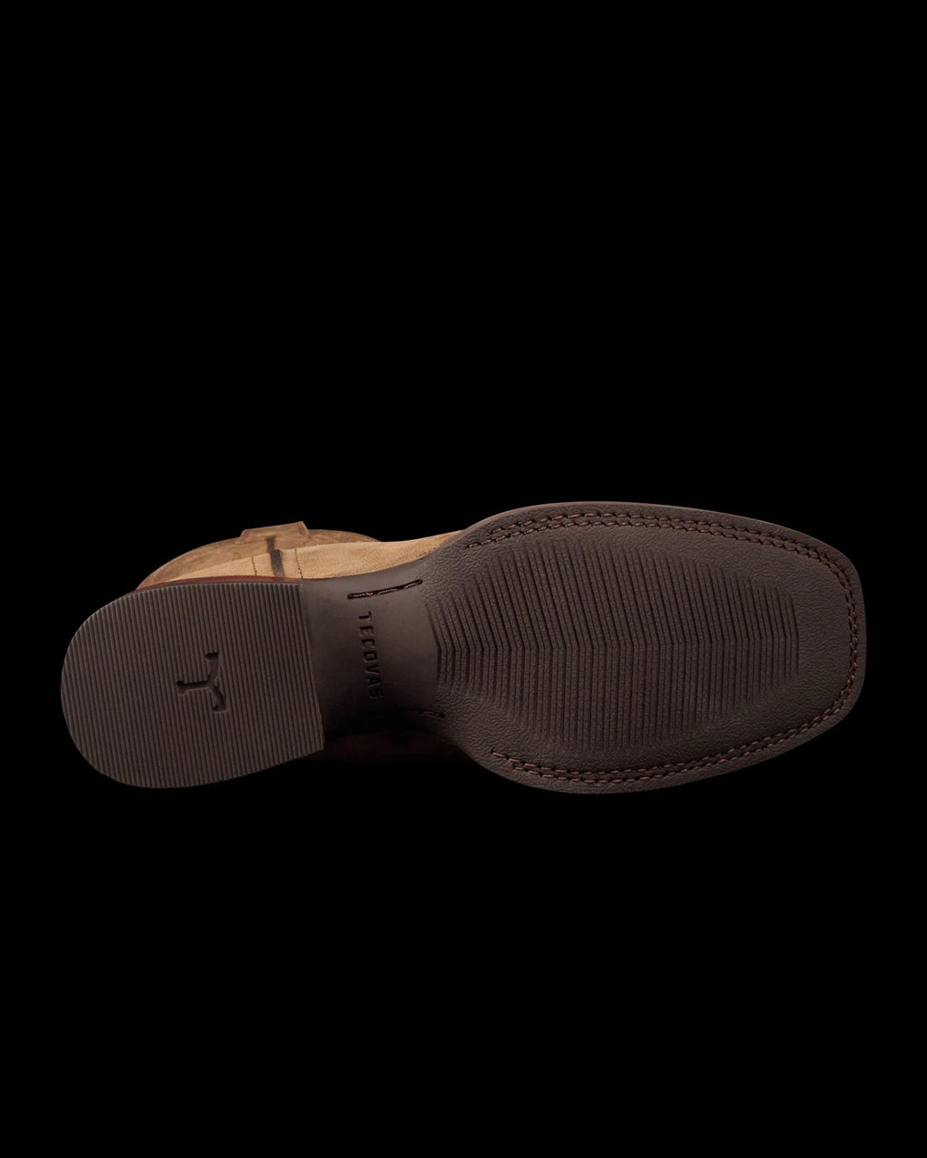 The image shows the bottom view of a brown dress shoe with visible textured grip patterns and a small logo near the heel, resembling styles found at The Tess Goat Cafe.