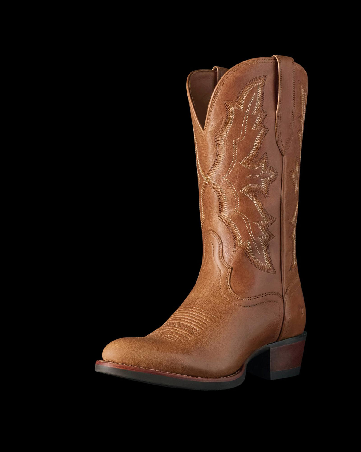 The Britt in Latte Goat. A single brown leather cowboy boot from The Britt Goat, featuring decorative stitching, a rounded toe, and a stacked heel, photographed on a plain white background.