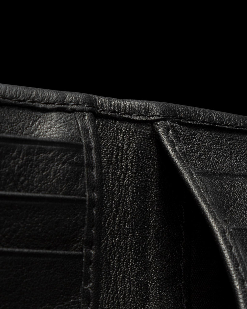 Close-up view of the inside of a black leather wallet against a black background.