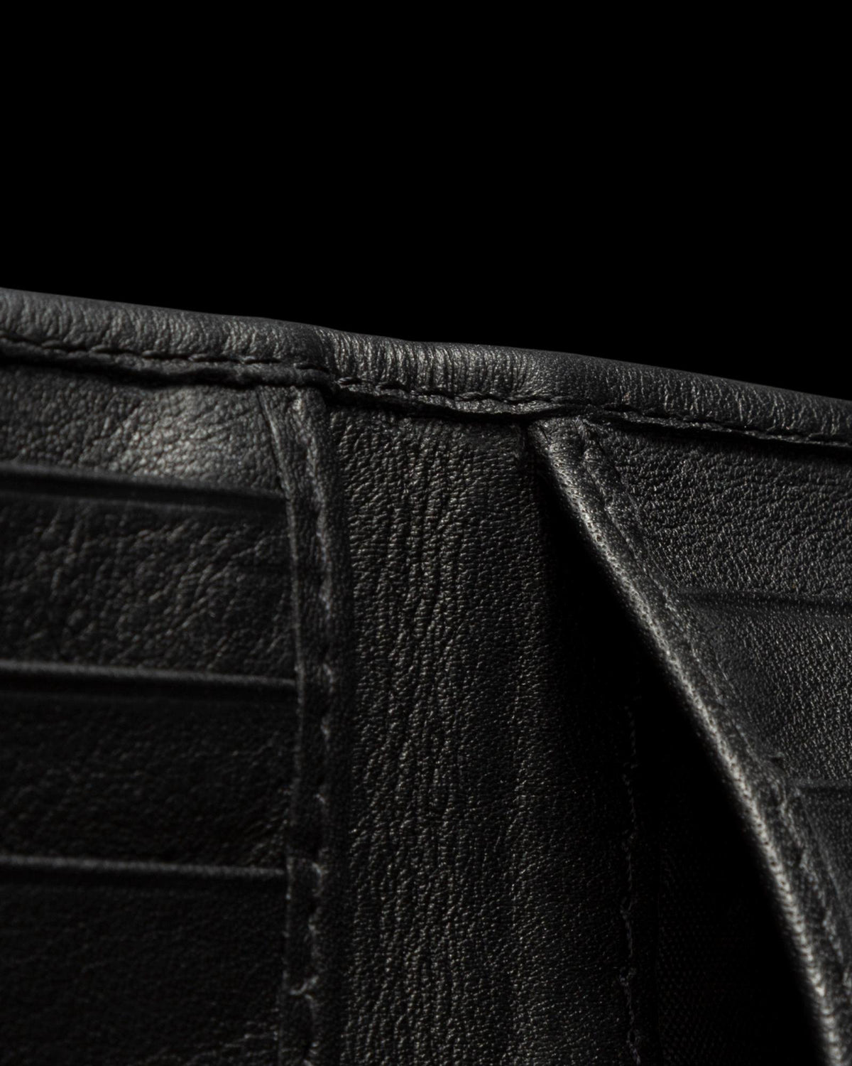 Close-up view of the inside of a black leather wallet against a black background.
