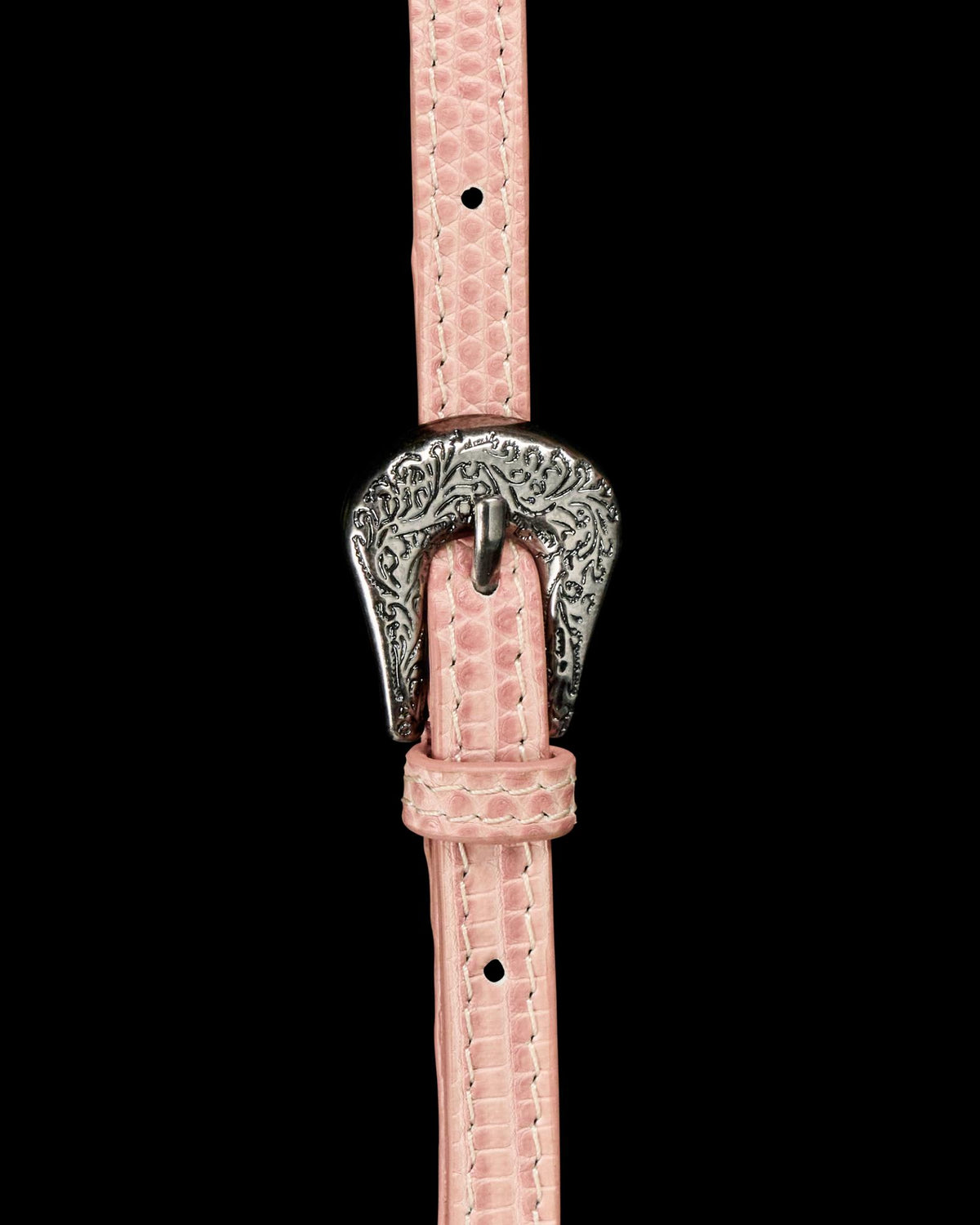 Close-up of a pink textured belt with an ornate silver buckle featuring an engraved floral pattern.