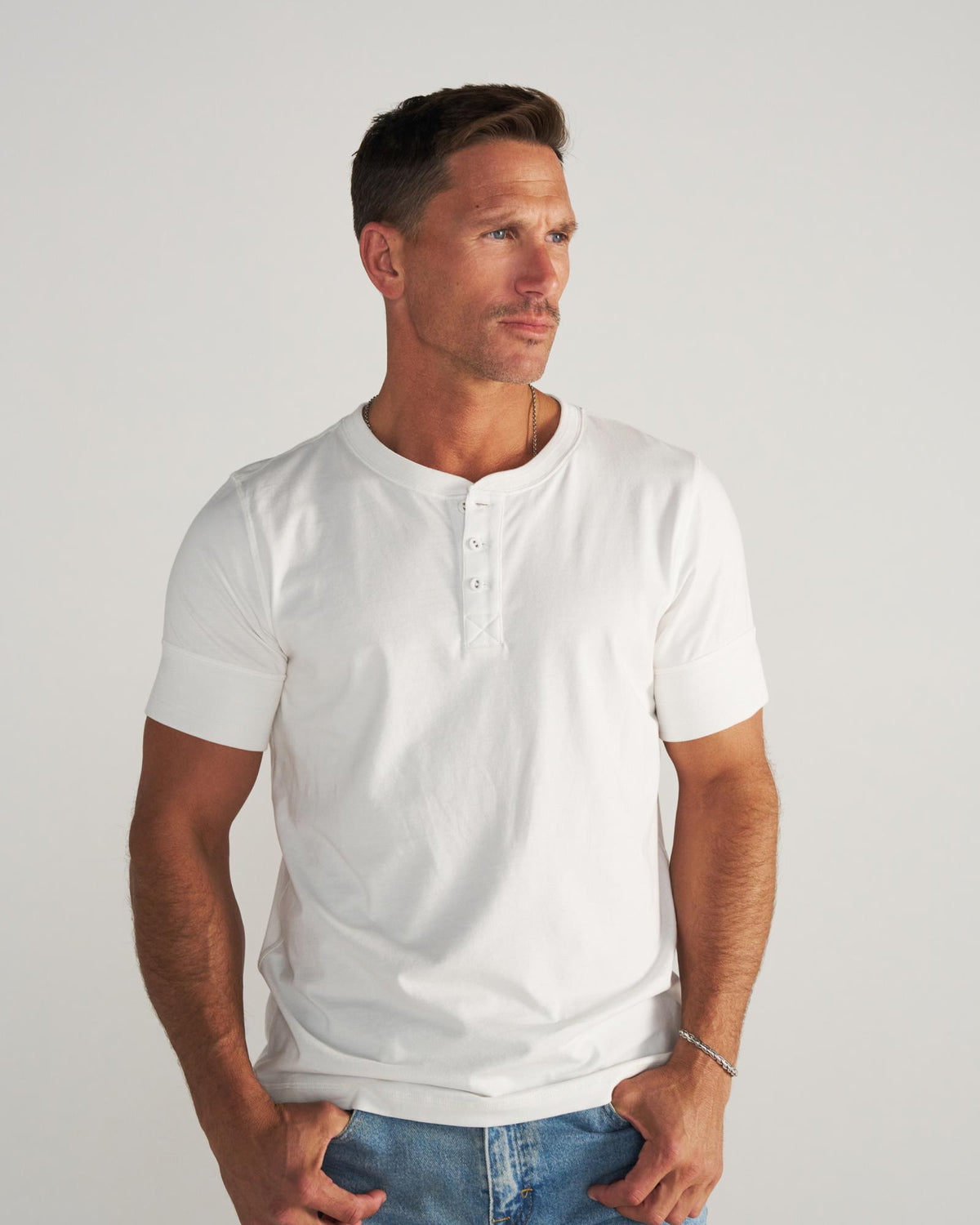 Man wearing a white henley in a photo studio