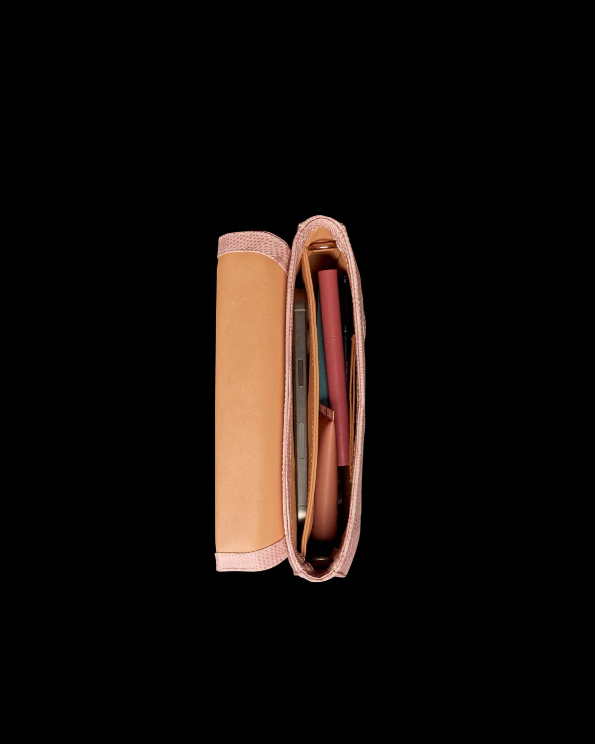 Top view of an open beige and pink purse containing several items, including a pen and what appears to be a mobile phone, against a plain white background.