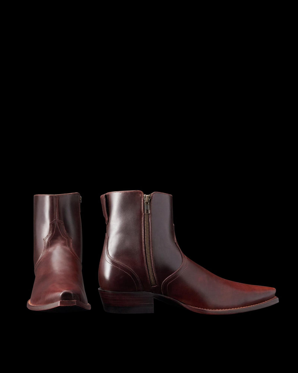 Two brown leather ankle boots with zippers, featuring a slight heel and a pointed toe, are displayed against a plain background.