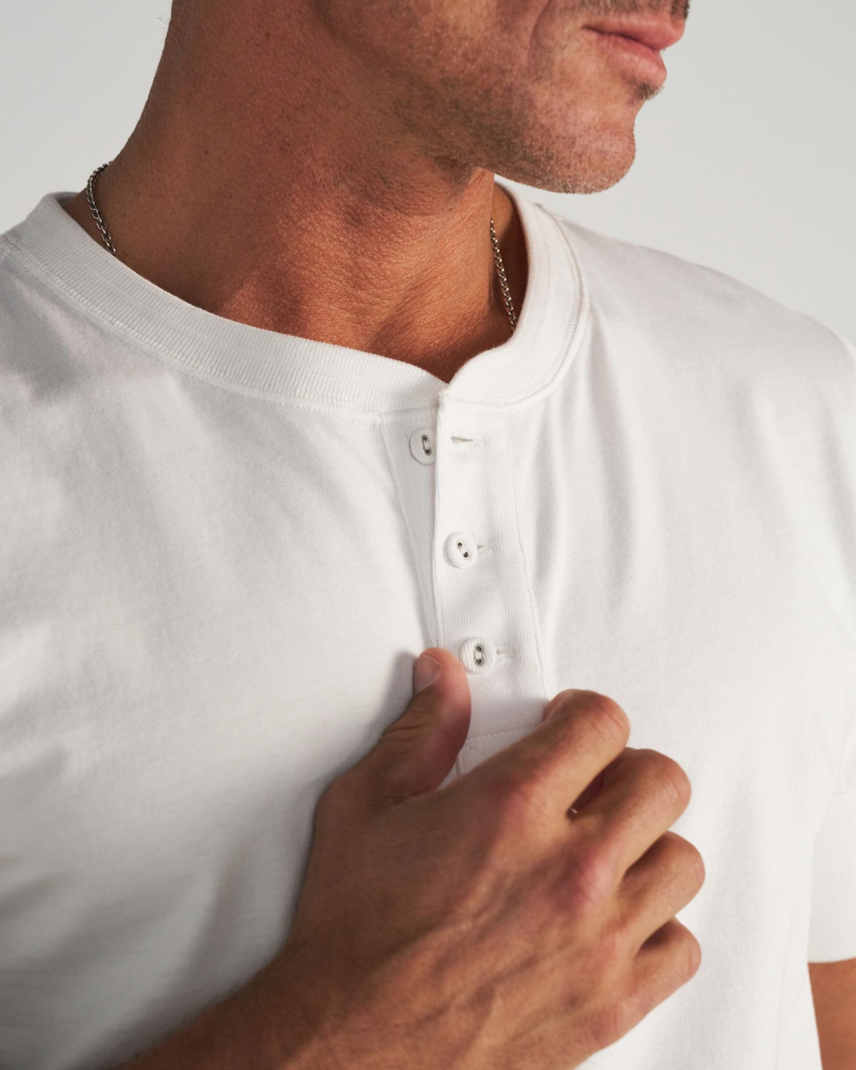 Man wearing a white henley in a photo studio