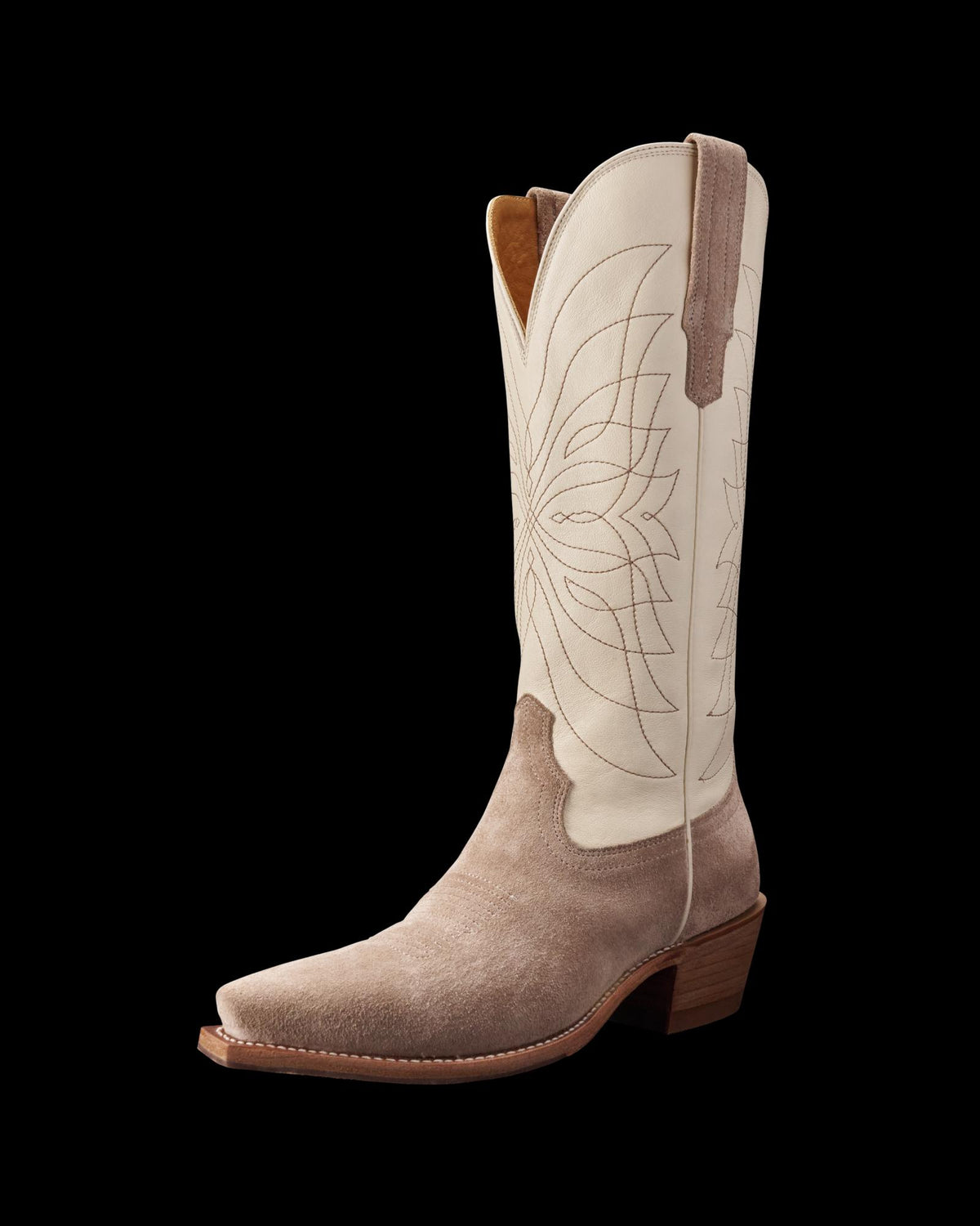 A single cowboy boot with a light beige upper, decorative stitching, and a tan suede lower section. It features a pointed toe and a wooden heel.