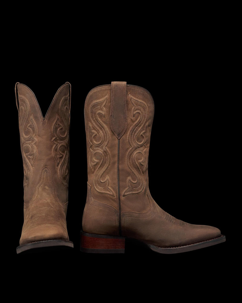 The Tess in Cafe Goat. A pair of brown leather cowboy boots with decorative stitching, inspired by The Tess Goat, one boot standing upright and the other displaying the front view.