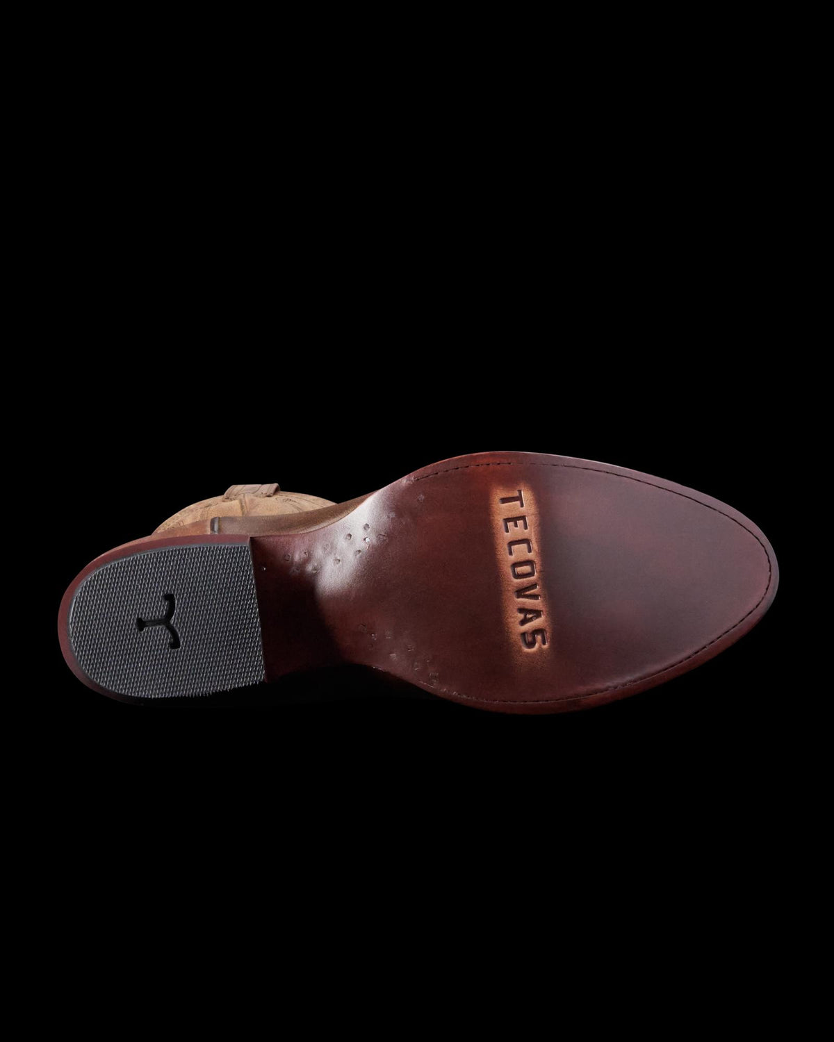 Underside view of a brown leather shoe with "Tecovas" engraved on the sole and a textured heel.
