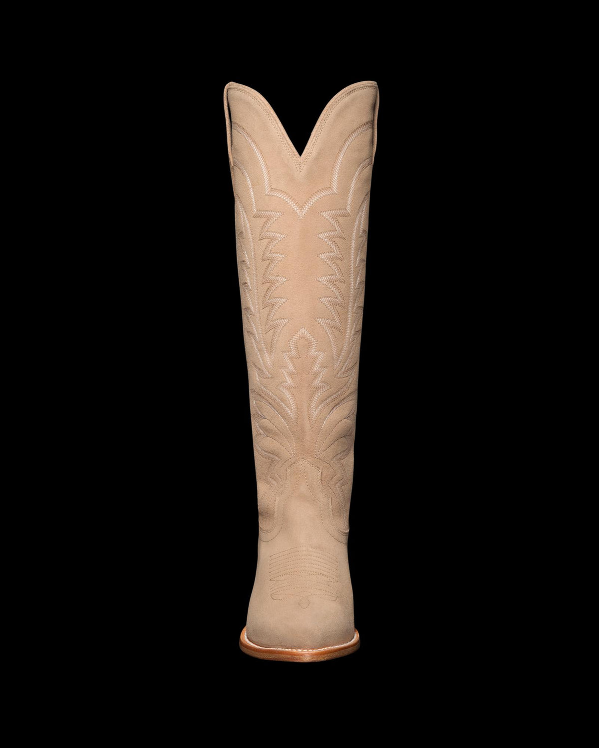 Tan cowboy boot with intricate stitched patterns on a black background.