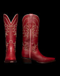 Two red cowboy boots with intricate stitching. One boot is shown from the front and the other from the side, displaying a pointed toe and a low heel, set against a black background.