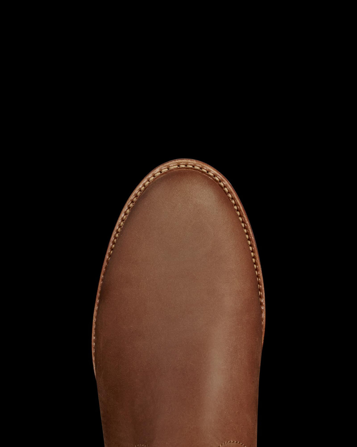 The Glen in Khaki Cowhide. A close-up of the toe area of a brown leather shoe crafted from supple cowhide, with visible stitching around the edge.