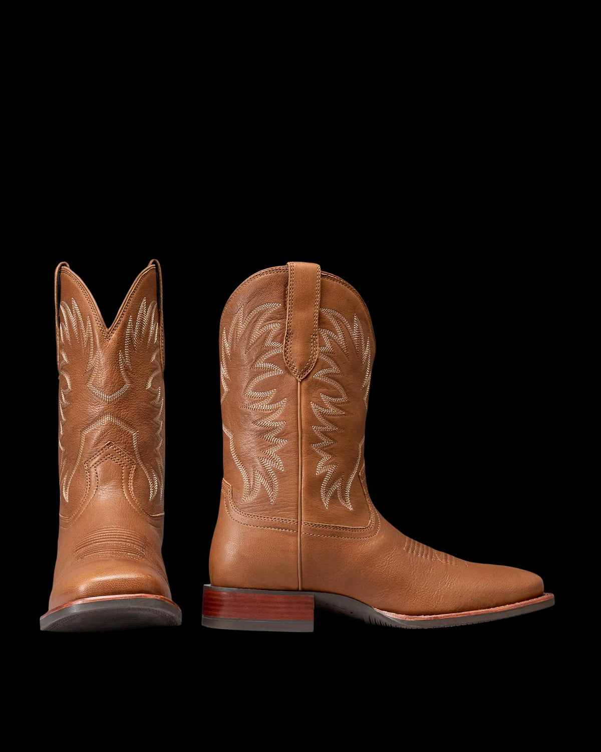 The Dusty in Mesa Goat. Pair of tan leather cowboy boots with decorative stitching, brown wooden heels, and pull straps—shown from side and front angles against a white background—crafted by The Dusty Goat for timeless Western style.
