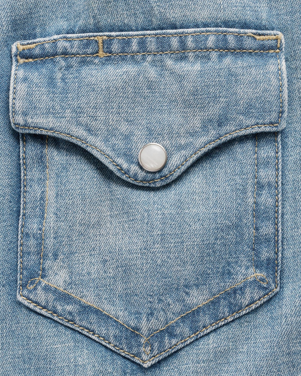Close-up of a light blue denim jacket pocket with a silver snap button and visible yellow stitching.