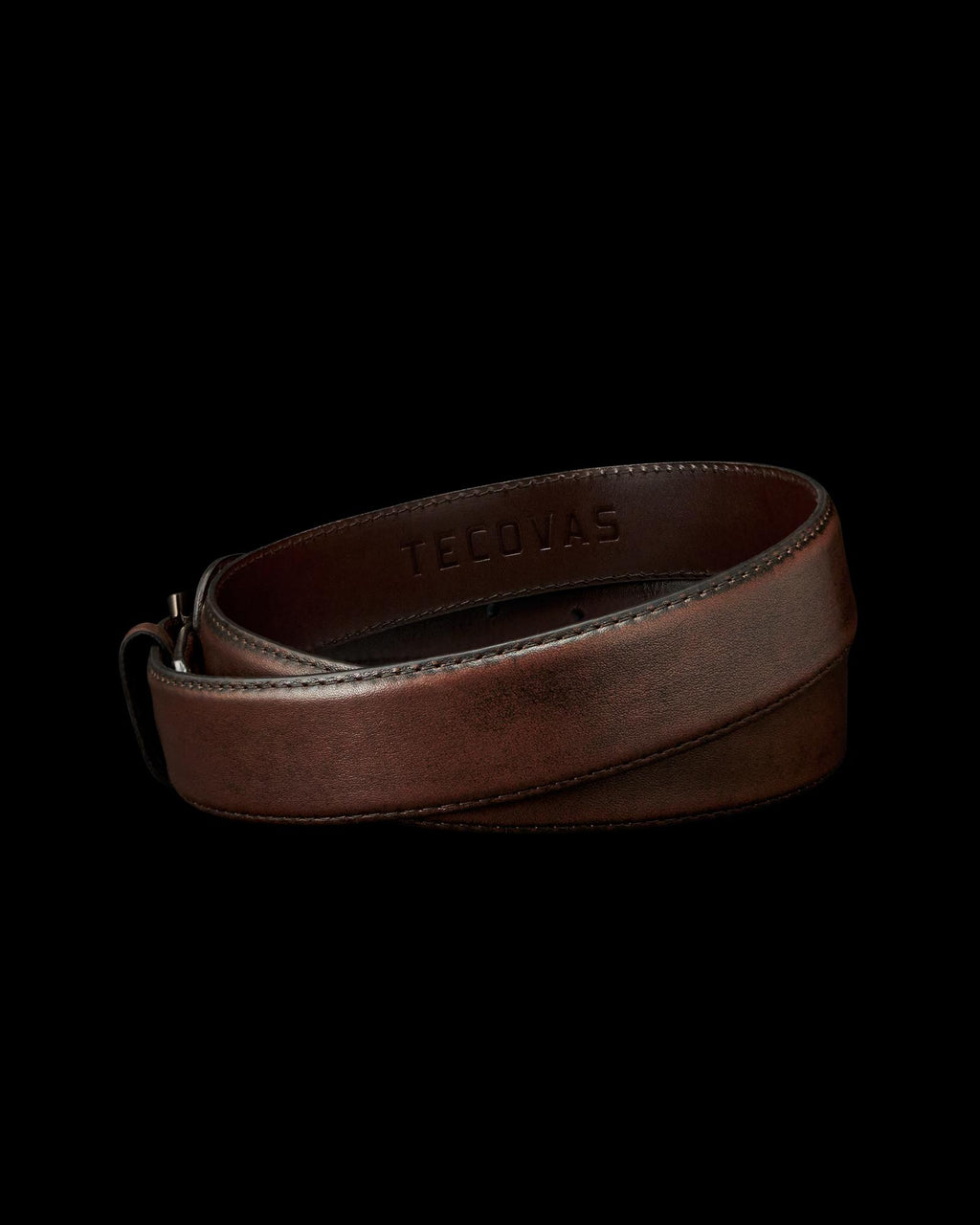 A rolled-up brown leather belt with the word "TECOVAS" embossed on the inside, displayed on a plain white background.