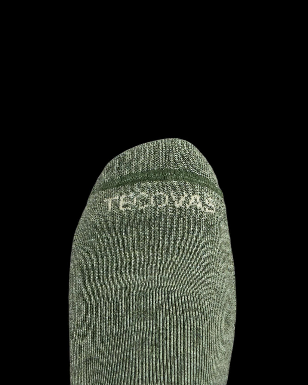 A close-up of a green sock with the word "Tecovas" in white text near the toe, against a plain white background.