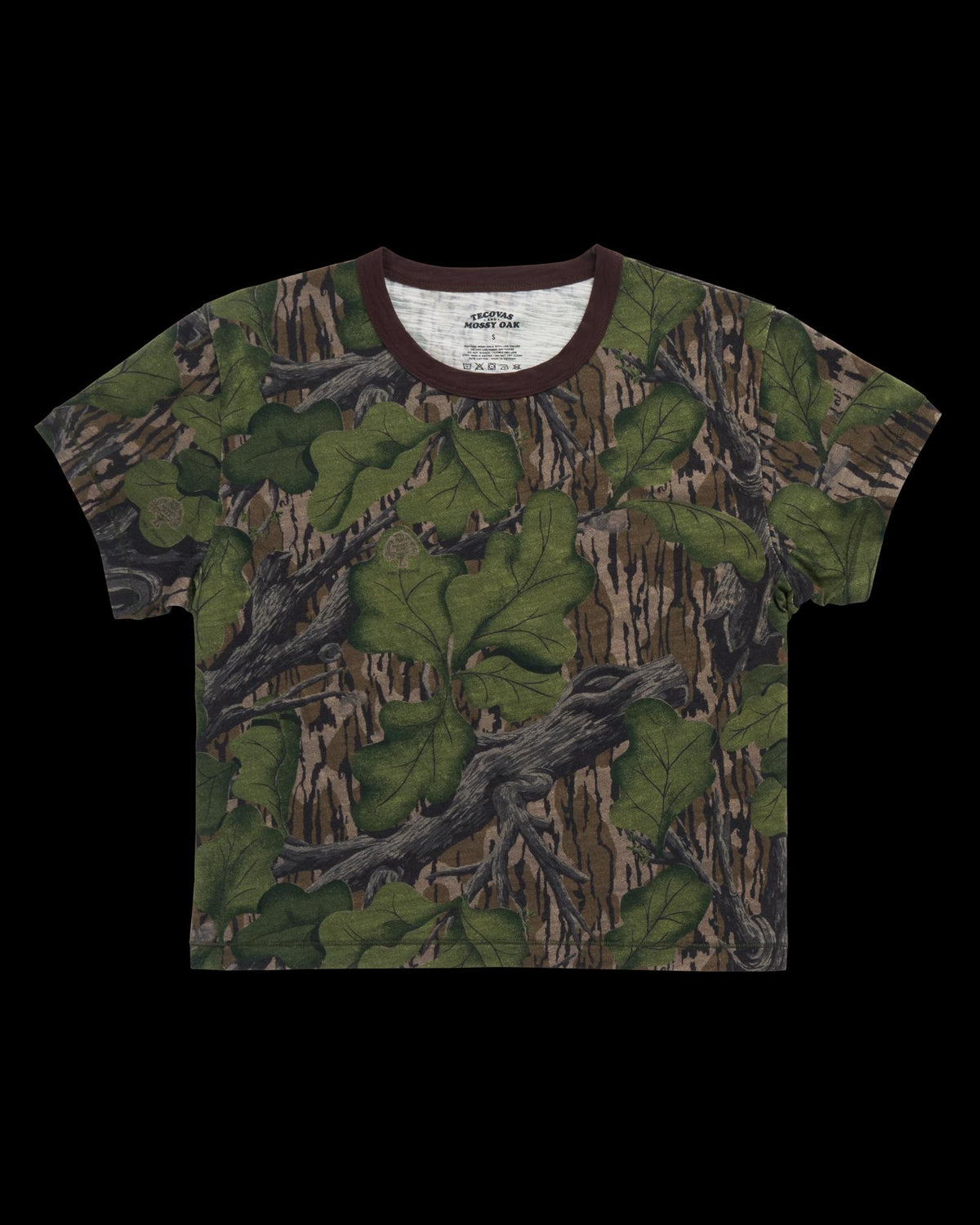 A short-sleeve t-shirt featuring a photorealistic forest camouflage pattern with green leaves, brown branches, and tree bark, displayed on a white background.