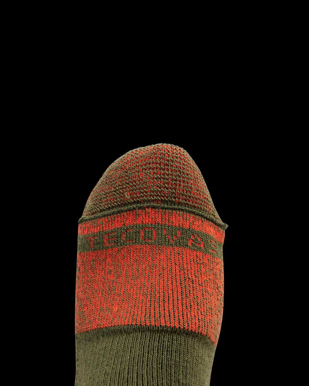 A close-up of a foot wearing a green and red sock with the word "PROVEN" partially visible across the toe area, set against a plain black background.