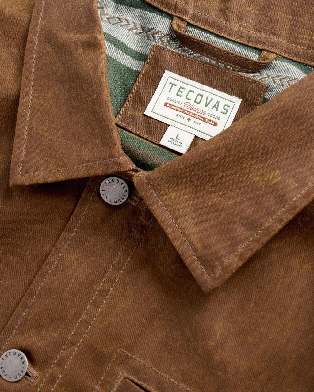 Brown jacket with a Tecovas brand label and plaid lining at the collar.