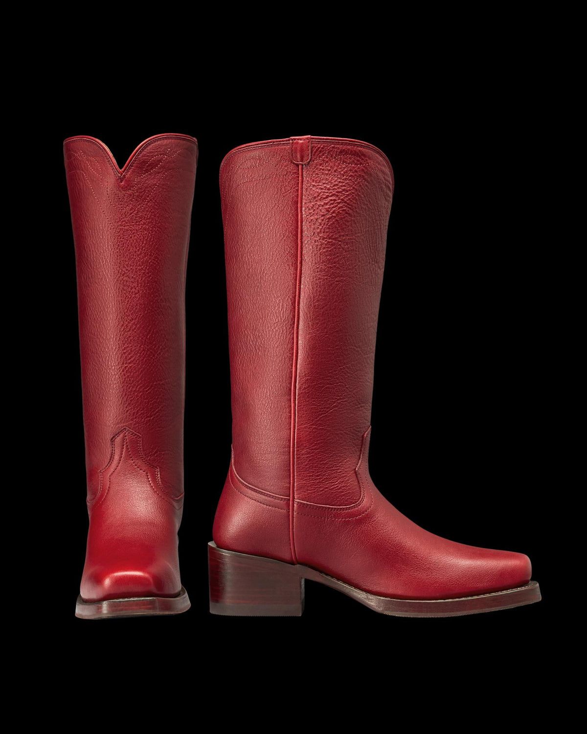 The Charlie in Scarlet Cowhide. Pair of tall, scarlet cowhide leather boots with block heels and a square toe, shown front and side view against a white background.