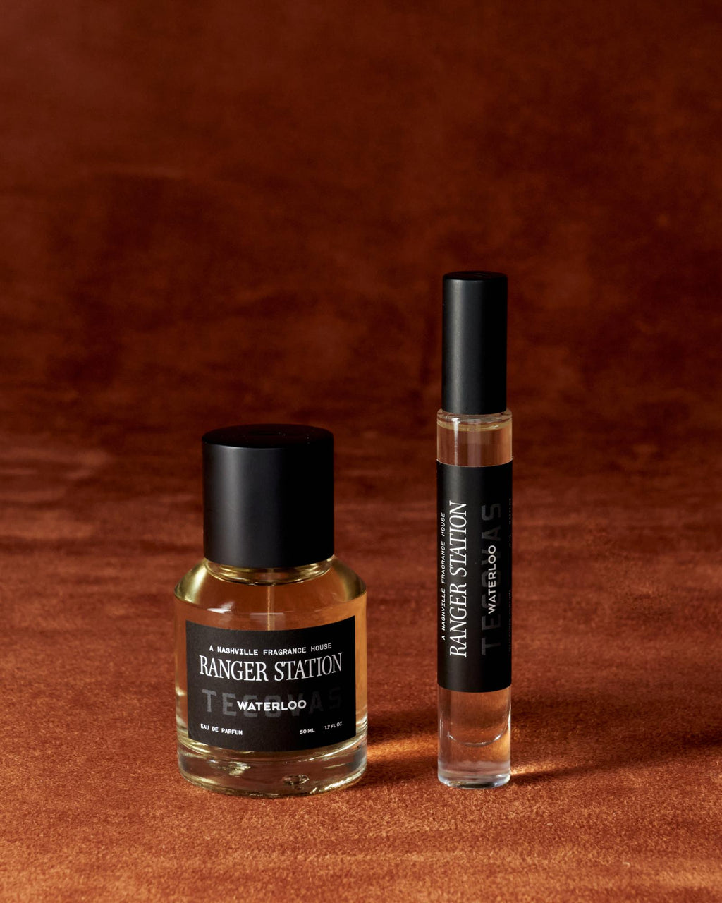 A bottle and a rollerball of Ranger Station Waterloo Eau de Parfum are placed on a brown textured surface.
