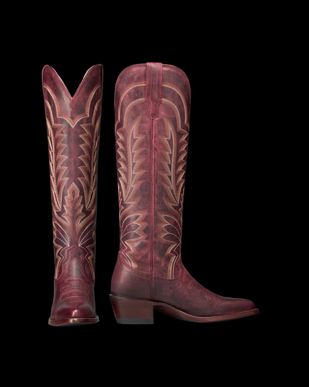 The Abby in Wine Goat. A pair of tall, burgundy leather cowboy boots from The Abby Goat, featuring decorative stitching and pointed toes, shown side by side on a white background.