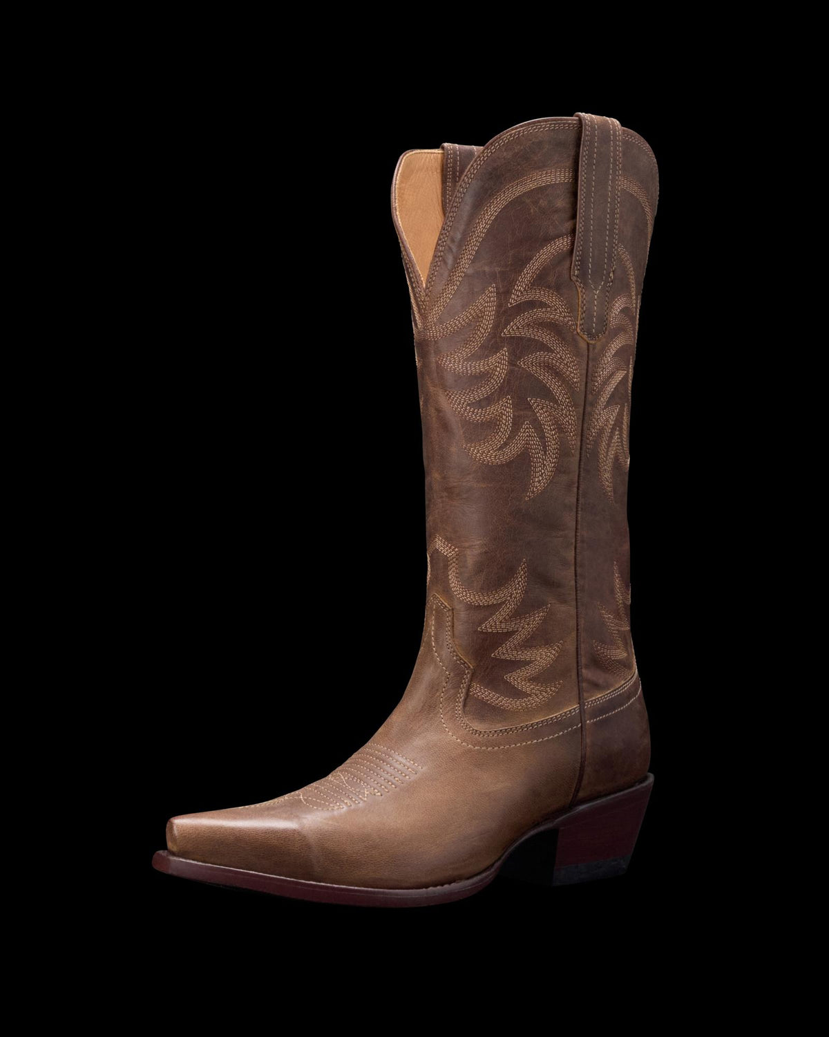 Brown leather cowboy boot with decorative stitching, pointed toe, and mid-height heel on a black background.