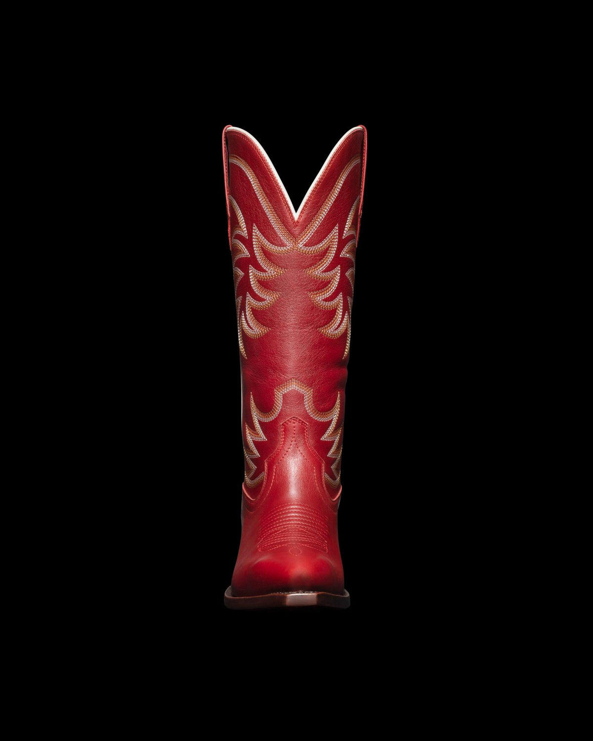 Red leather cowboy boot with intricate stitching, viewed from the back, set against a black background.