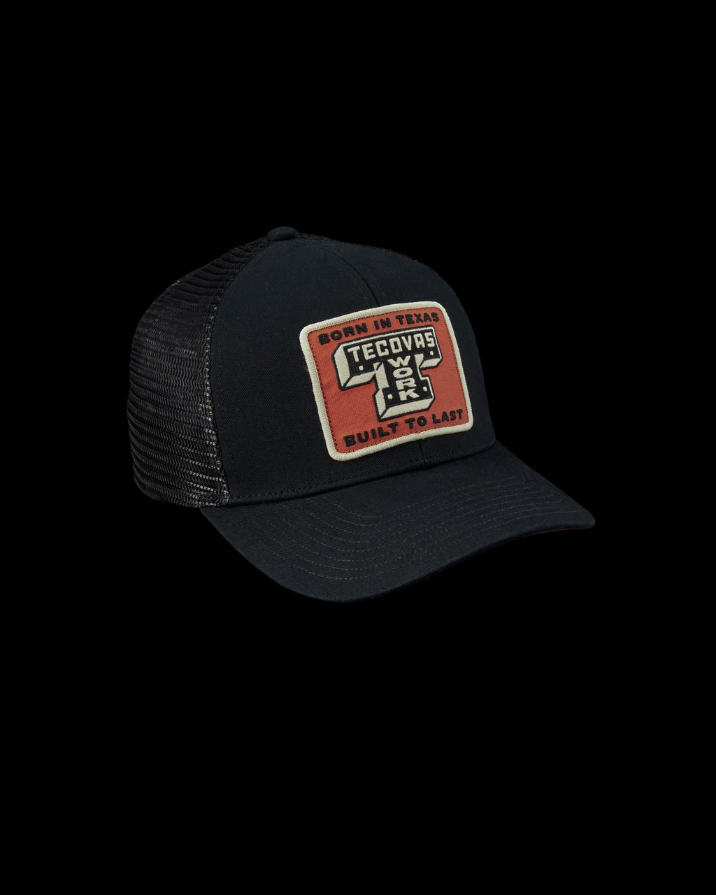 Black mesh trucker hat with a curved brim and a red patch on the front reading "Born in Texas Tecovas Built to Last.