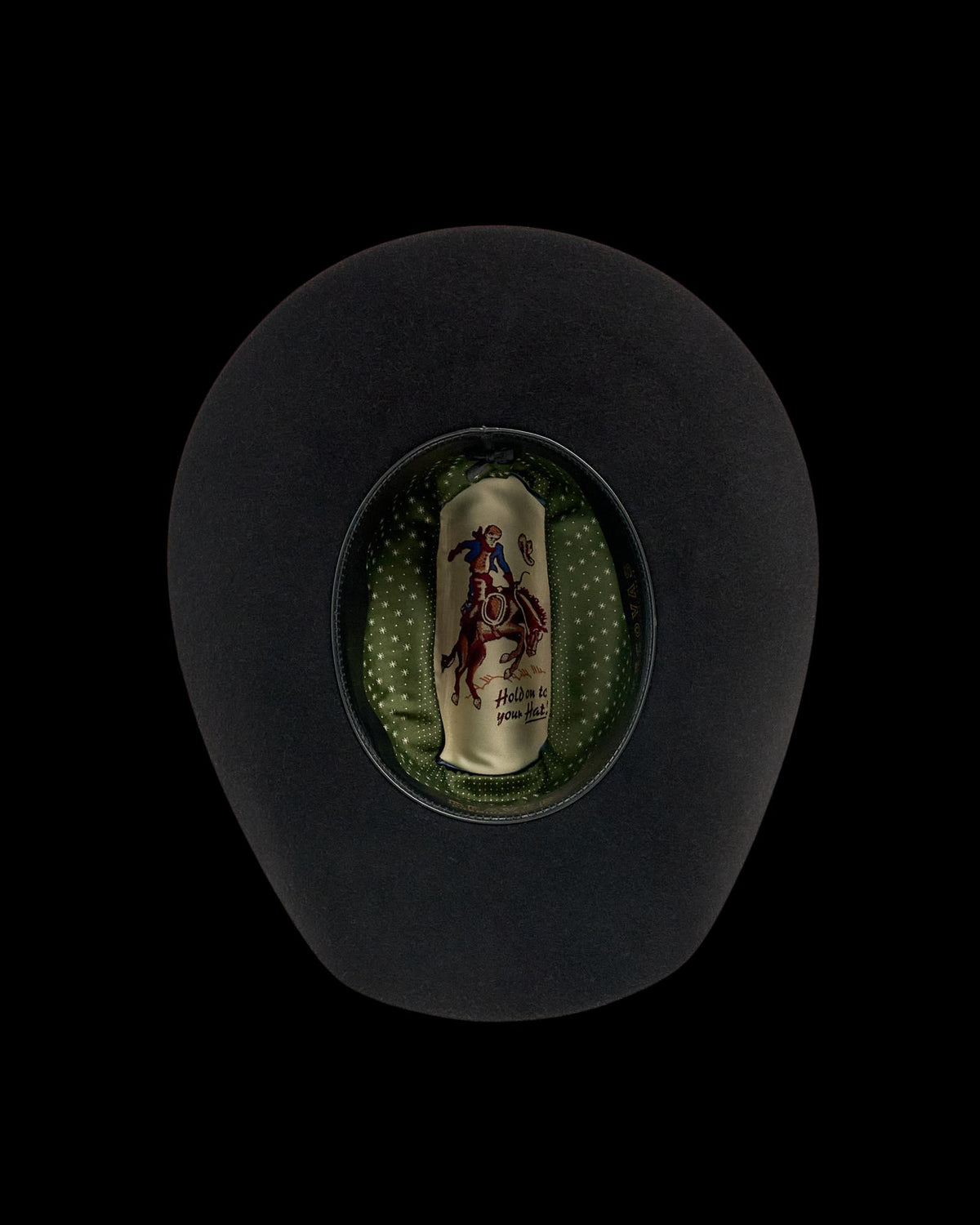 Black cowboy hat shown from above, revealing a green polka dot inner lining and a label with a rider on a horse.