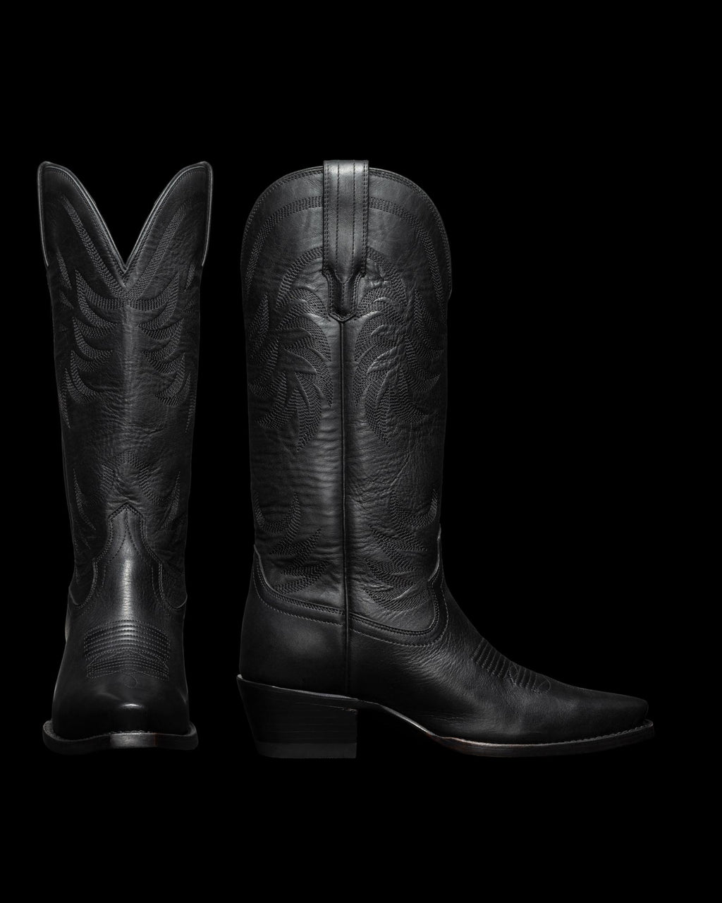 Two black cowboy boots with intricate stitching patterns are shown; one boot is seen from the side and the other from the back.