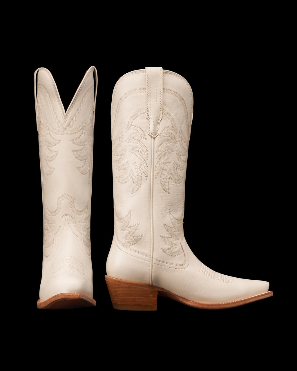 Two white cowboy boots with decorative stitching, showing side and rear views. They have brown stacked heels and pointed toes.