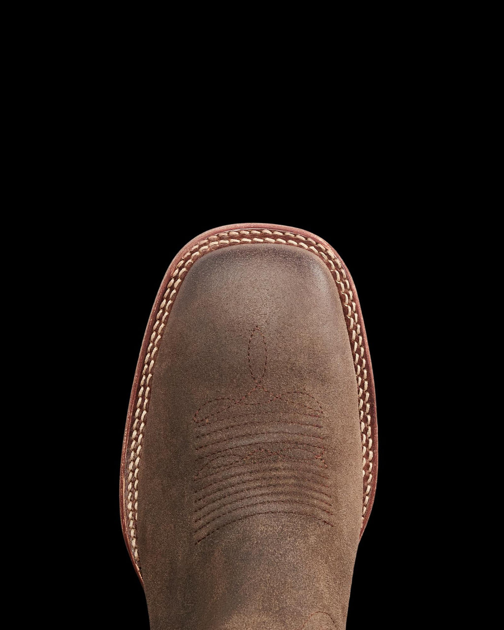 The Doc in Moss Suede. Top view of a brown leather cowboy boot with decorative stitching, white welt stitching around the toe, and subtle accents of rich Moss Suede for added texture.
