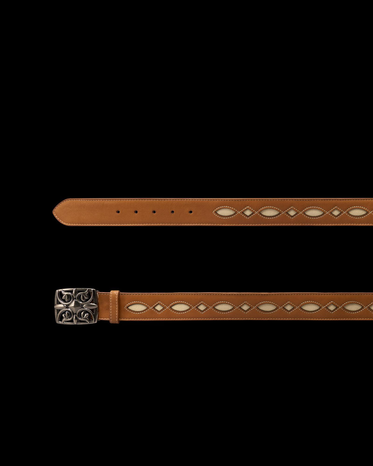 Tan leather belt with white diamond-shaped cutout details and a silver buckle featuring a raised decorative pattern, displayed flat on a white background.