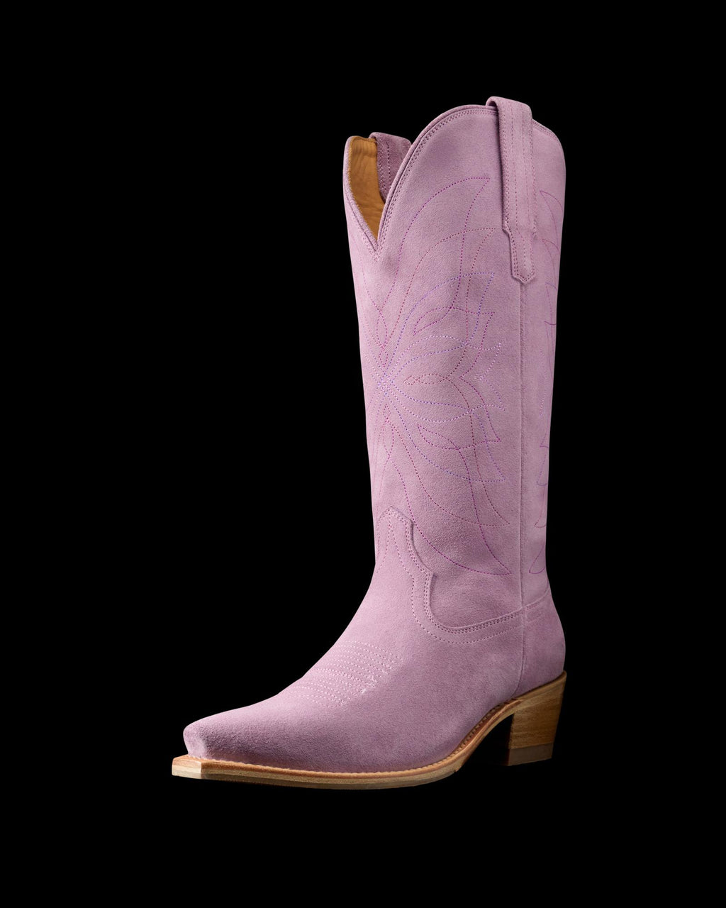 The Annie in Lavender Suede. A single pink Annie Suede cowboy boot with decorative stitching, a pointed toe, wooden heel, and pull tabs on either side.