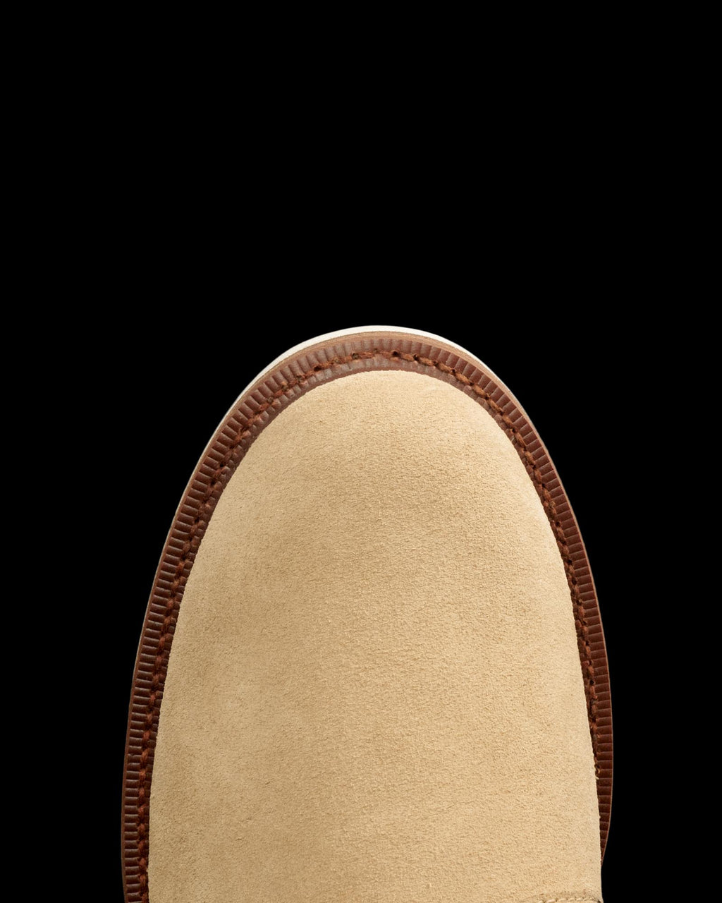 Close-up of the toe of a Sandstone Roughout suede shoe with a brown leather trim, from The Knox Lace Up Shearling Roughout collection, against a white background.
