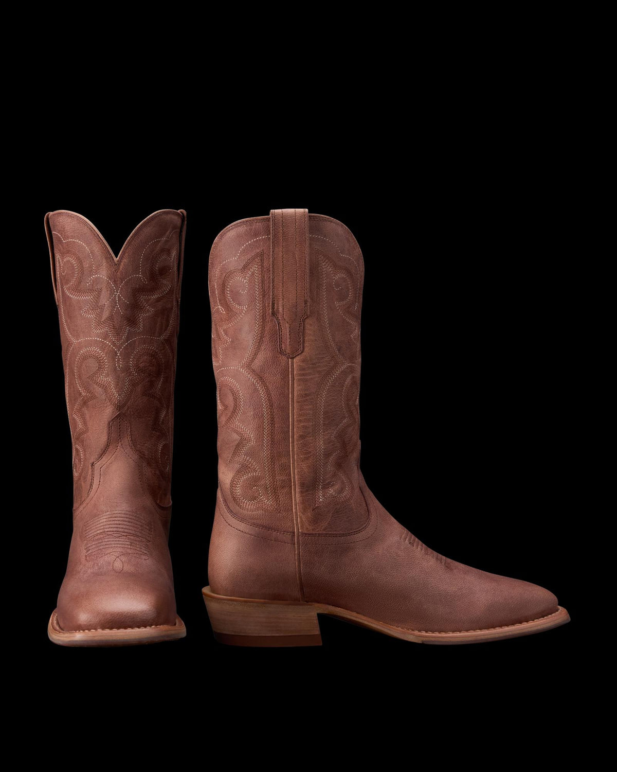A pair of brown leather cowboy boots with decorative stitching, shown from the front and side against a white background.