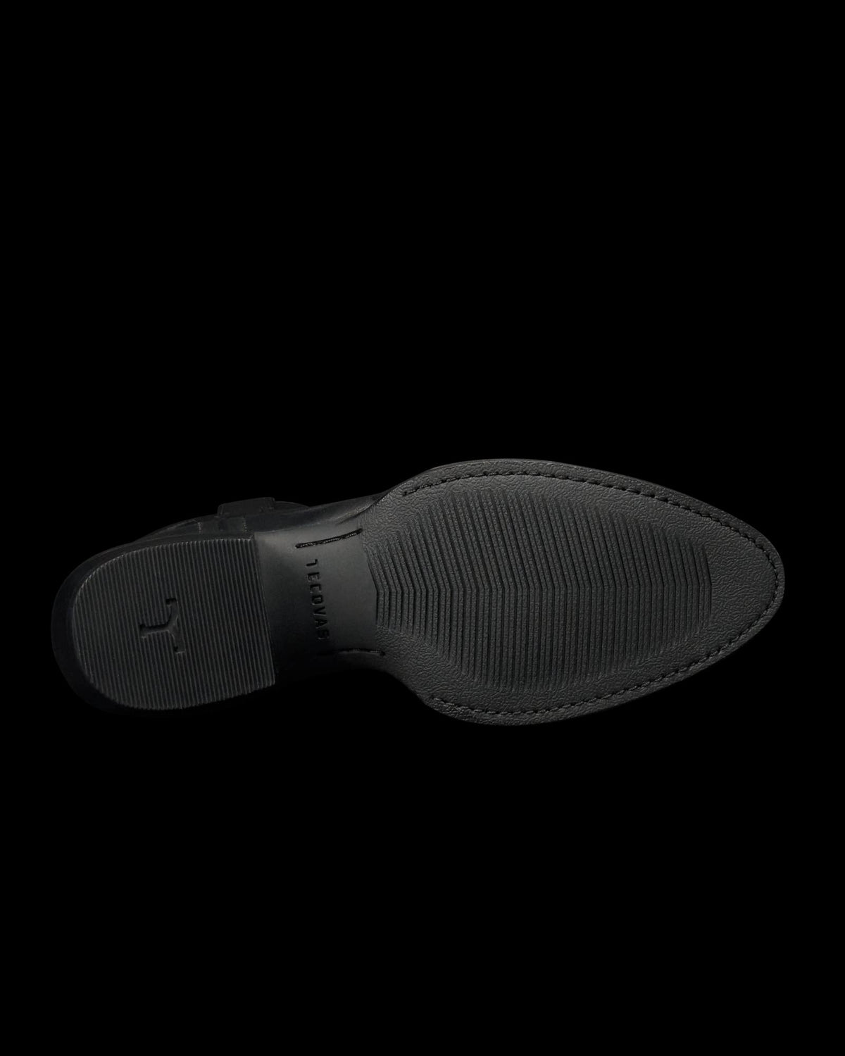 The Britt in Midnight Cowhide. The image shows the black rubber sole of The Britt Cowhide dress shoe, viewed from the bottom, featuring textured grip patterns and subtle branding near the heel.
