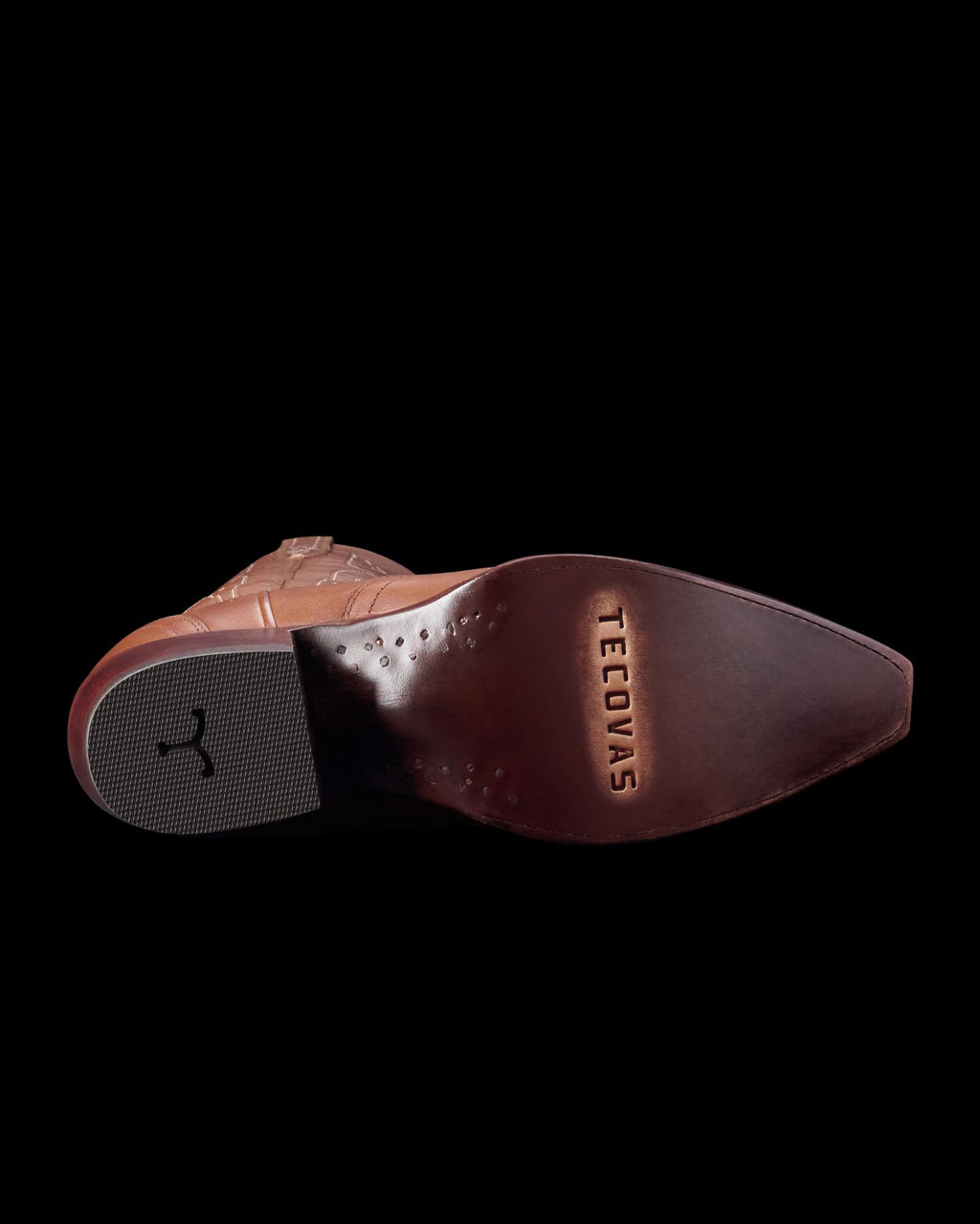 Sole of a brown leather cowboy boot with "Tecovas" engraved. The heel has a black rubber grip.