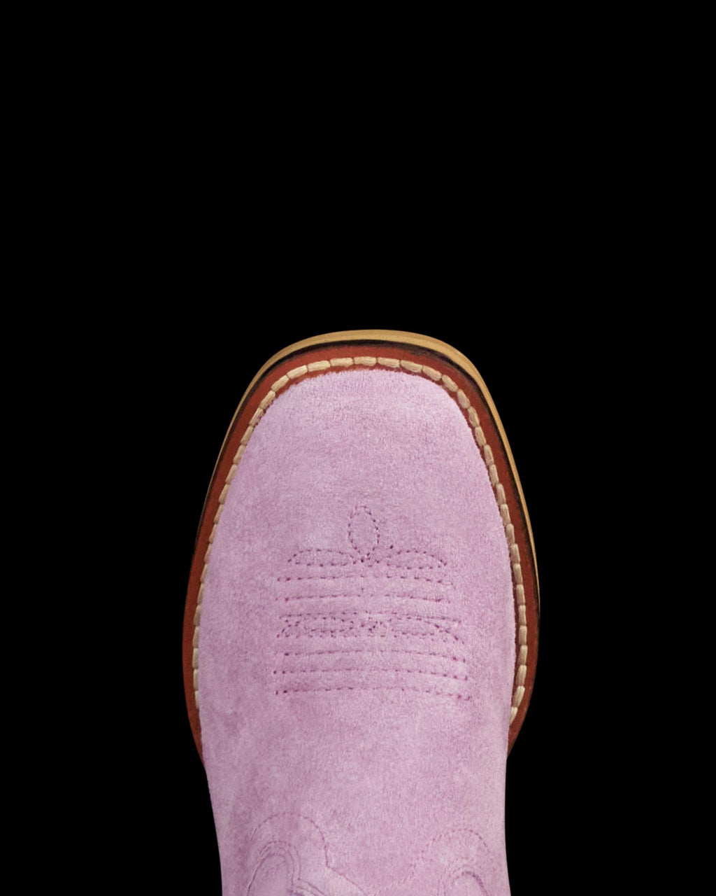 Close-up of the toe of a pink suede cowboy boot with decorative stitching, visible brown sole, and white welt stitching.