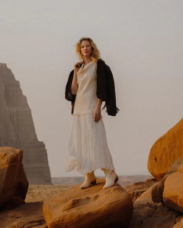 A woman wearing a light dress in a desert landscape